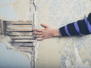 Hand is touching an old exposed plaster lath wall