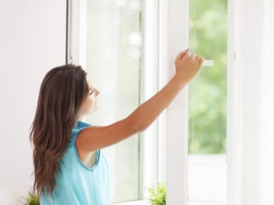 Woman opening window to let in fresh air and improve indoor air quality