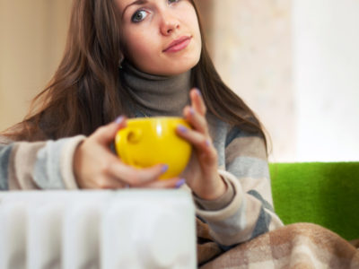 woman with yellow cup near radiator at home