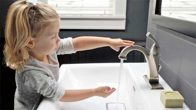 Child using touchless bathroom sink faucet