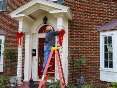 Woman on ladder putting Christmas decorations up