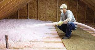 Man installing blown-in fiberglass insulation.