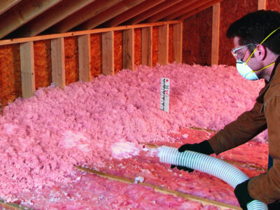 Man adding blowin in insulation to an attic