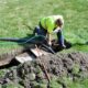 A workman pumping out a backyard septic tank.