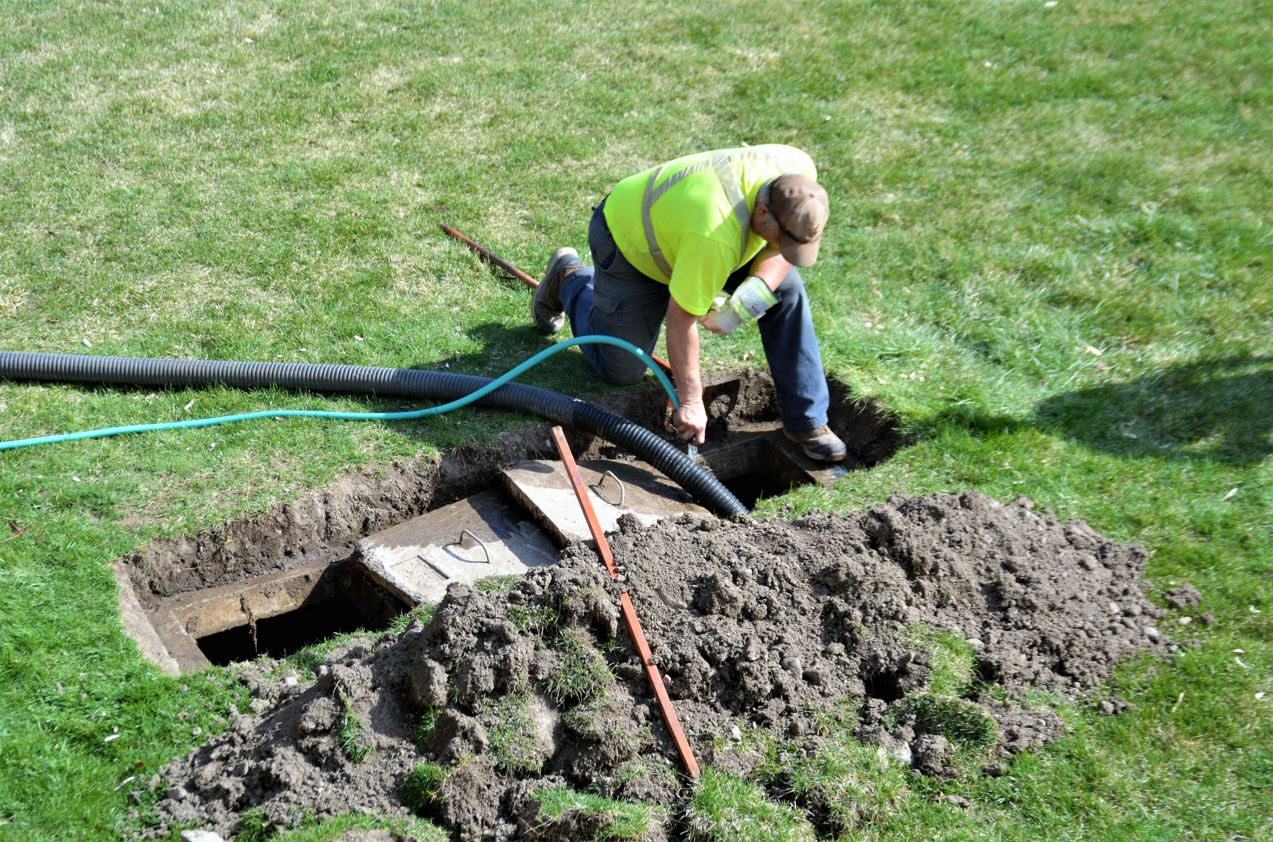 A workman pumping out a backyard septic tank.